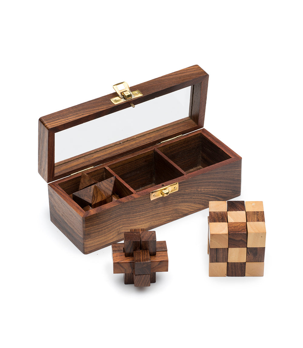 Open wooden puzzle box with brass latch, plus carved cube and checkered block pieces