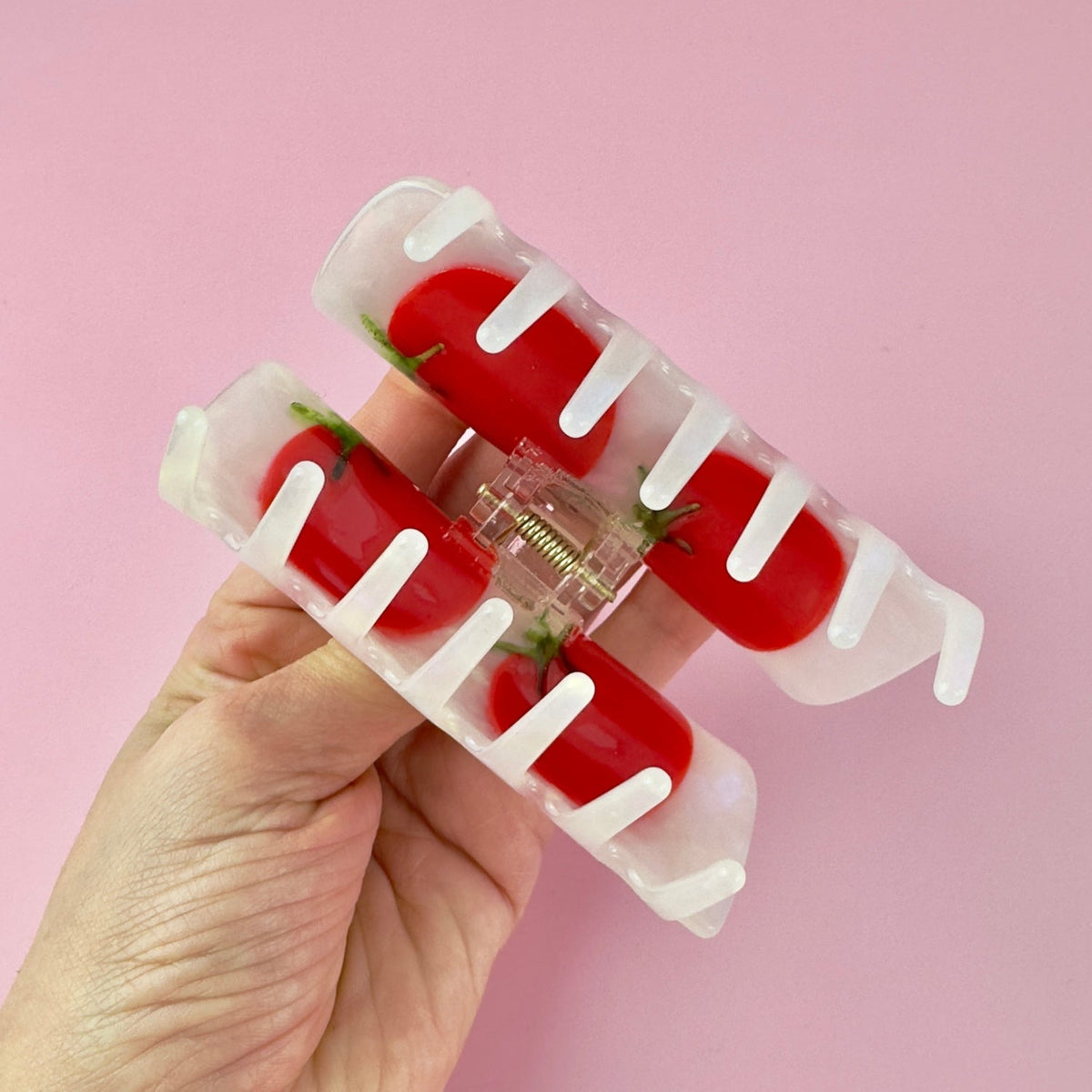 Tomato-themed hair claw clip held open; red tomato pieces on a clear base