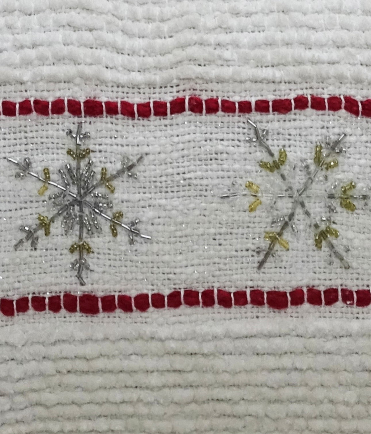 Close-up of decorative Christmas pillow fabric with red stripe border and snowflake embellishments