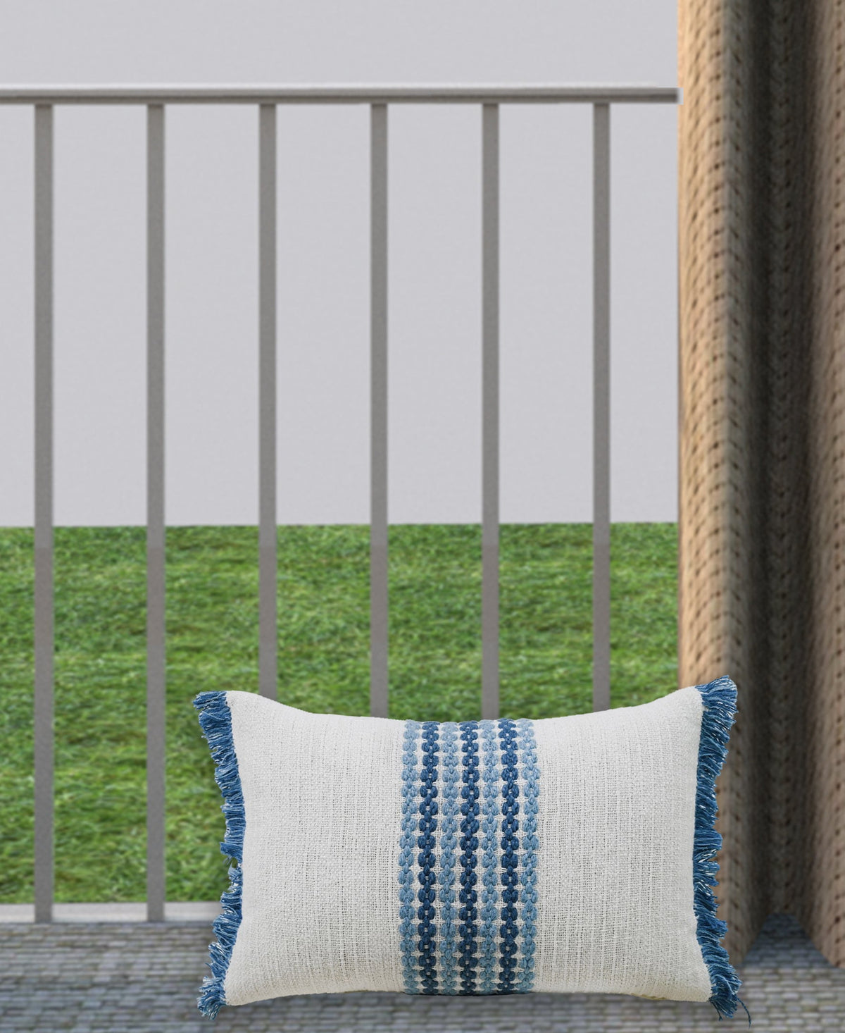 Decorative pillow on outdoor bench, off-white cover with blue vertical woven motif and fringe