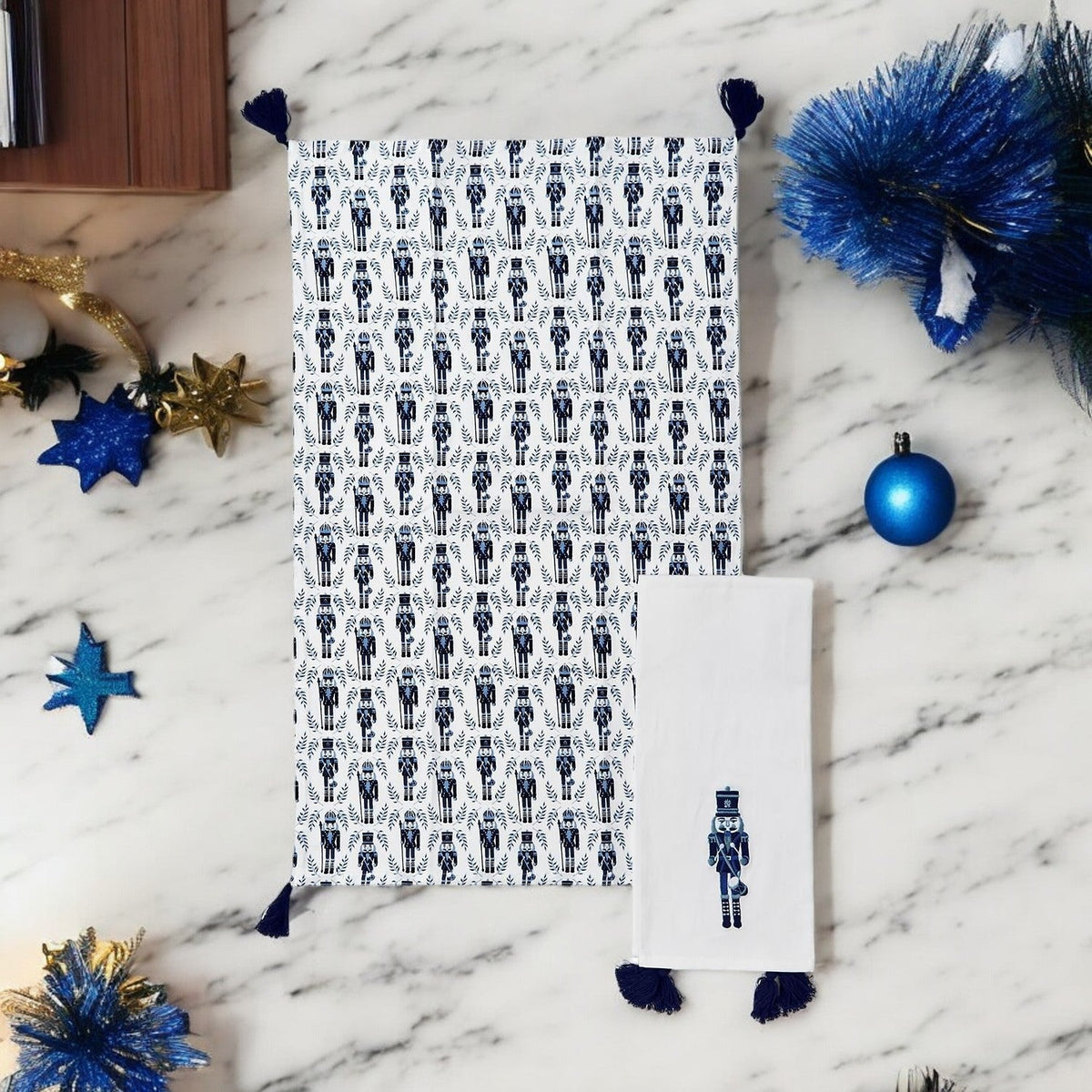 White tea towel with blue nutcracker print, navy tassel fringe, and nutcracker tag