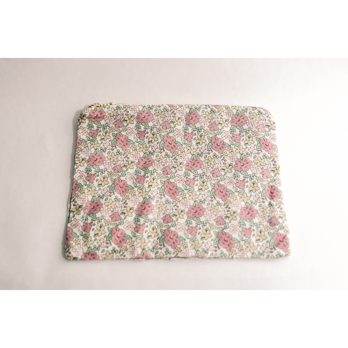 Flat floral zipper pouch with ruffle detailing and pink-and-green flower pattern.