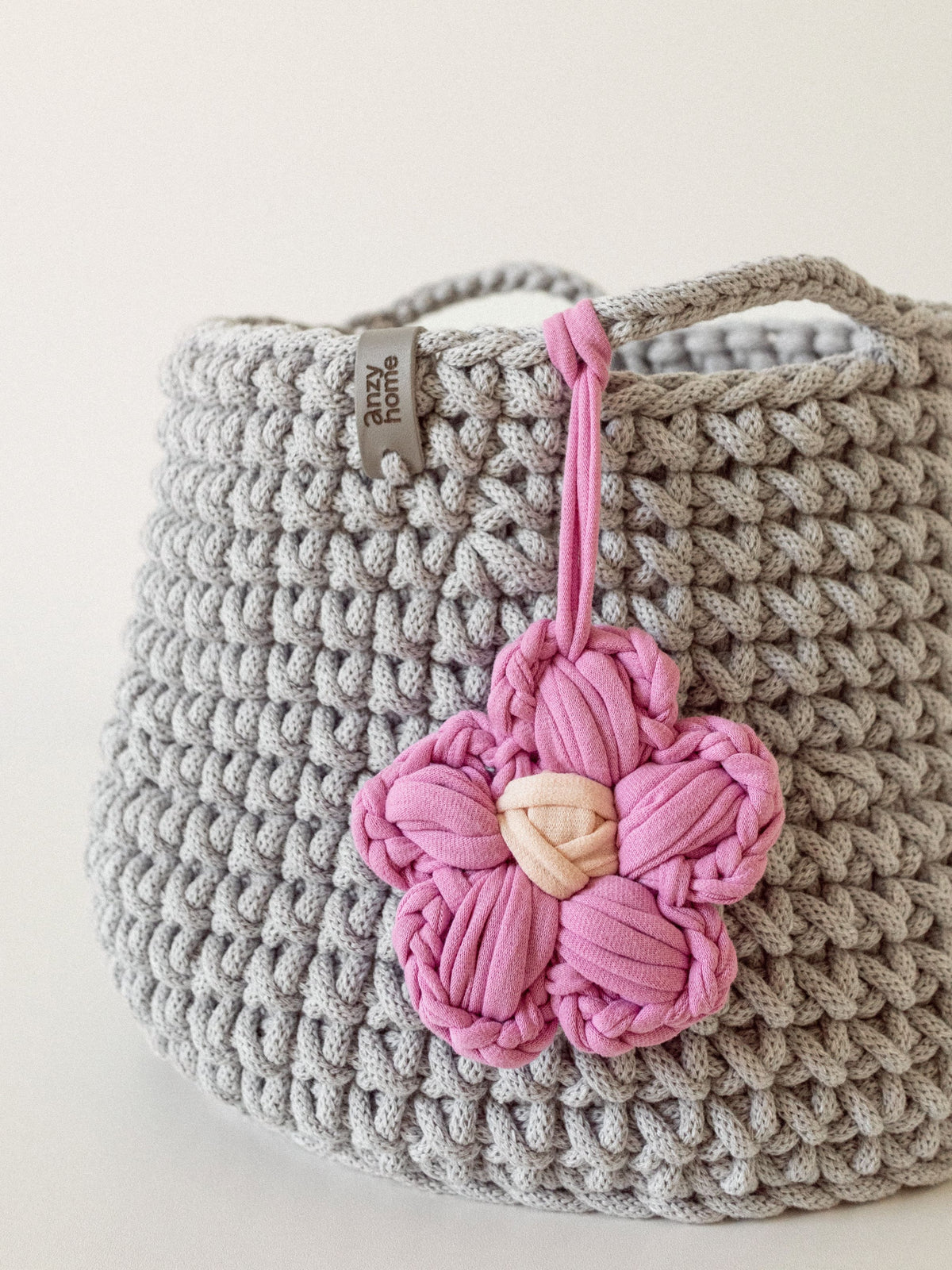 Crocheted nursery storage basket with pink flower charm