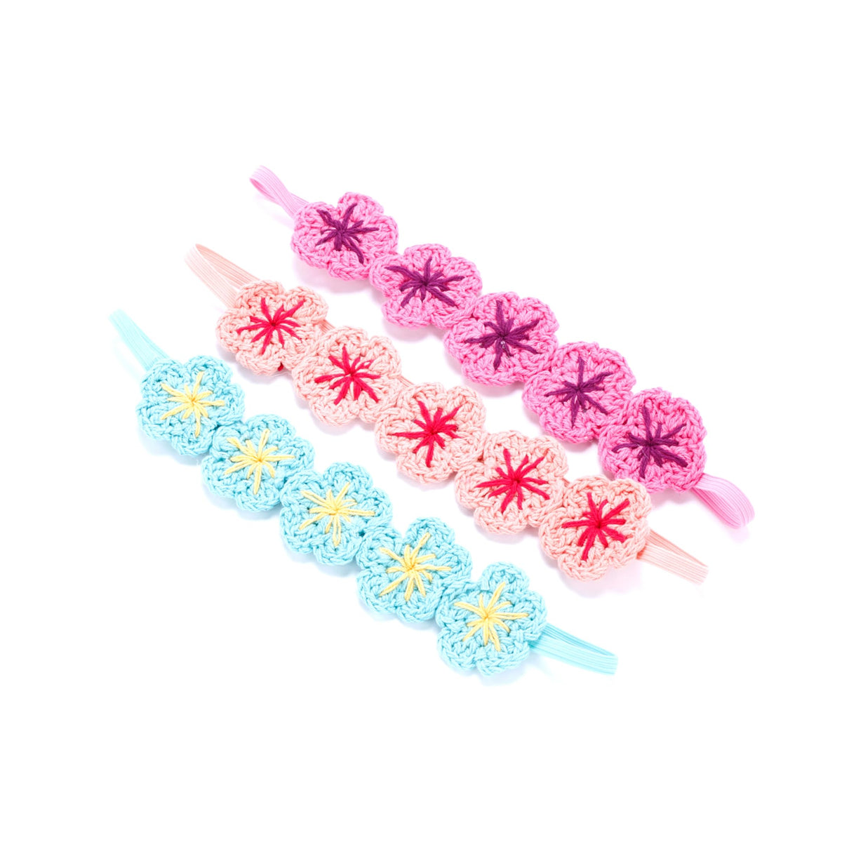 Three knit flower crown headbands in pink, pale pink, and blue