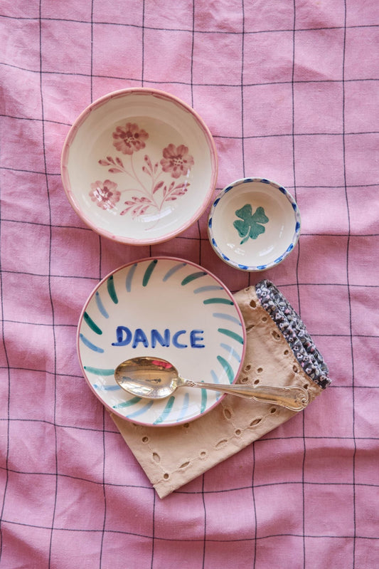 Small ceramic bowl with hand-painted pink flowers, cream interior, orange rim