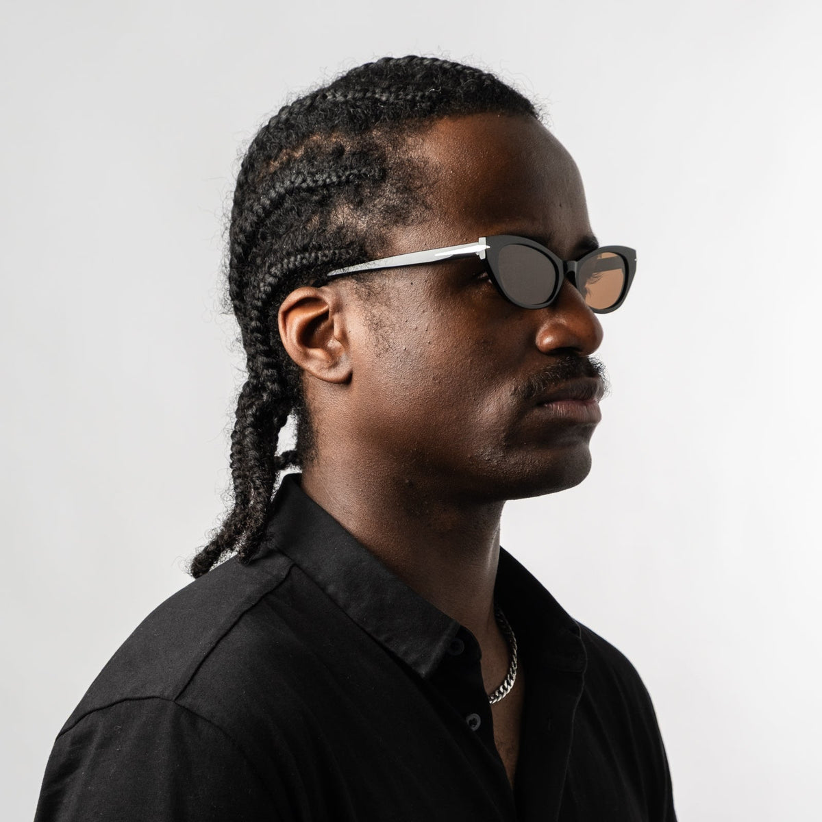 Person wearing black polarized sunglasses with bronze lenses, profile view.