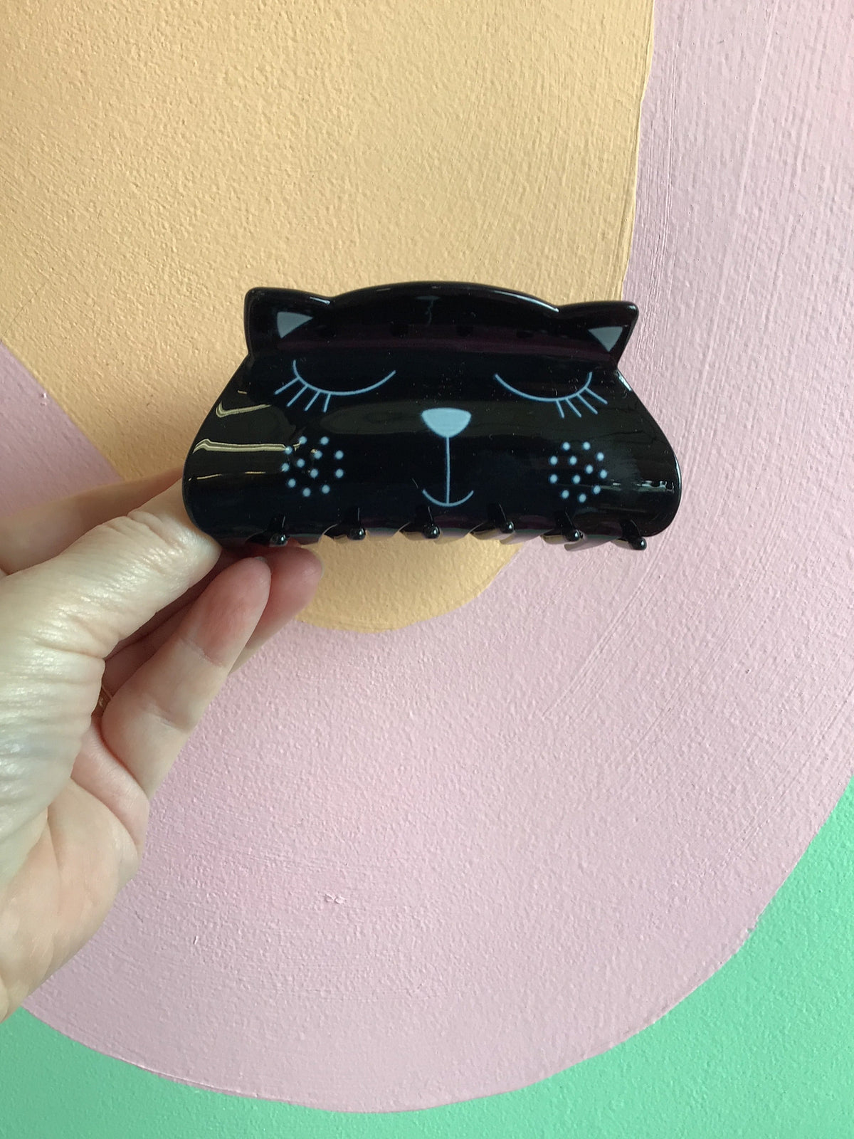 Black kitty hair claw with closed-eye face and glitter dot accents
