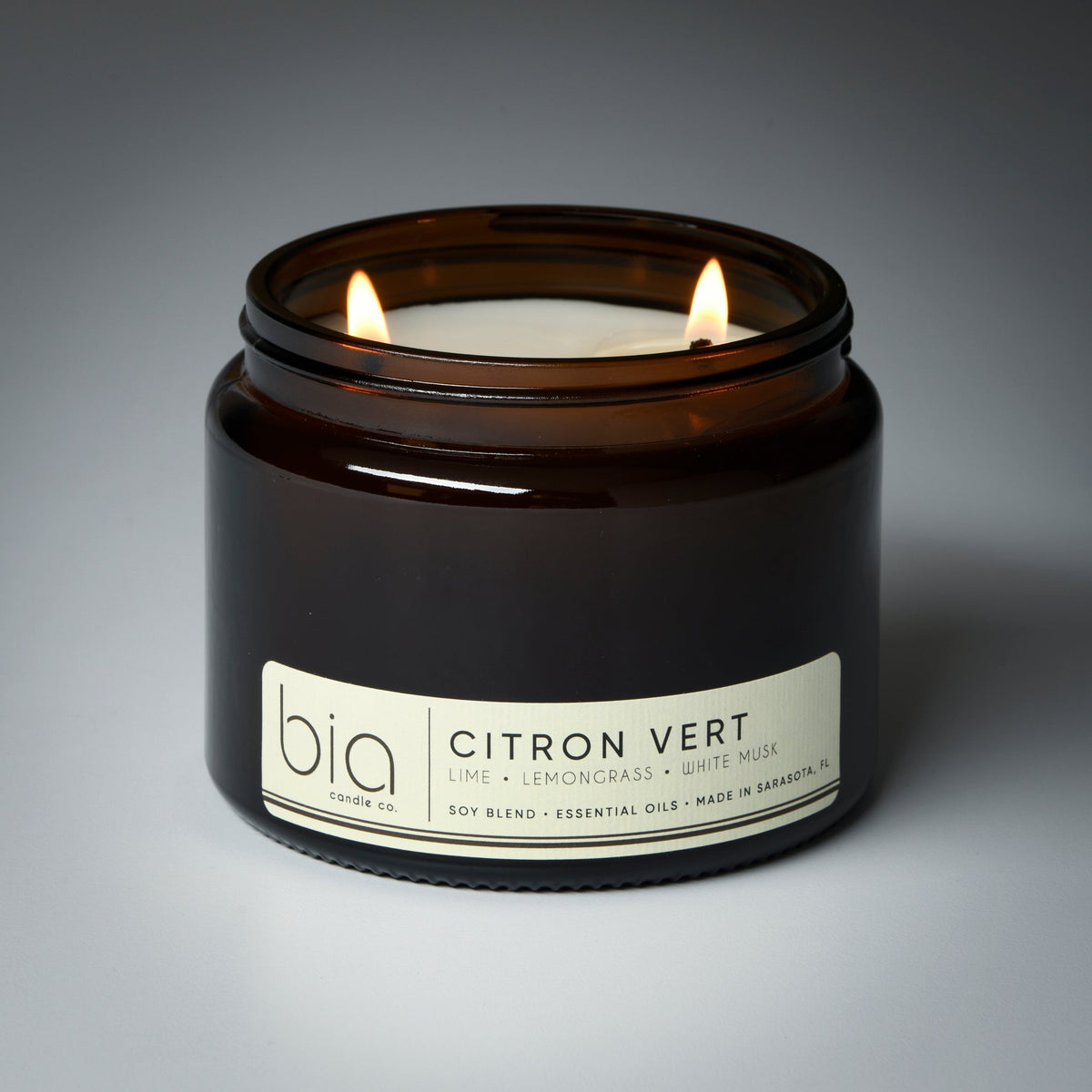Dark amber glass soy blend candle with flame and label reading Citron Vert