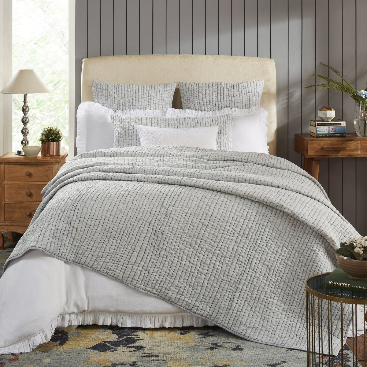Light gray stone-washed cotton quilt with textured weave, draped over bed.
