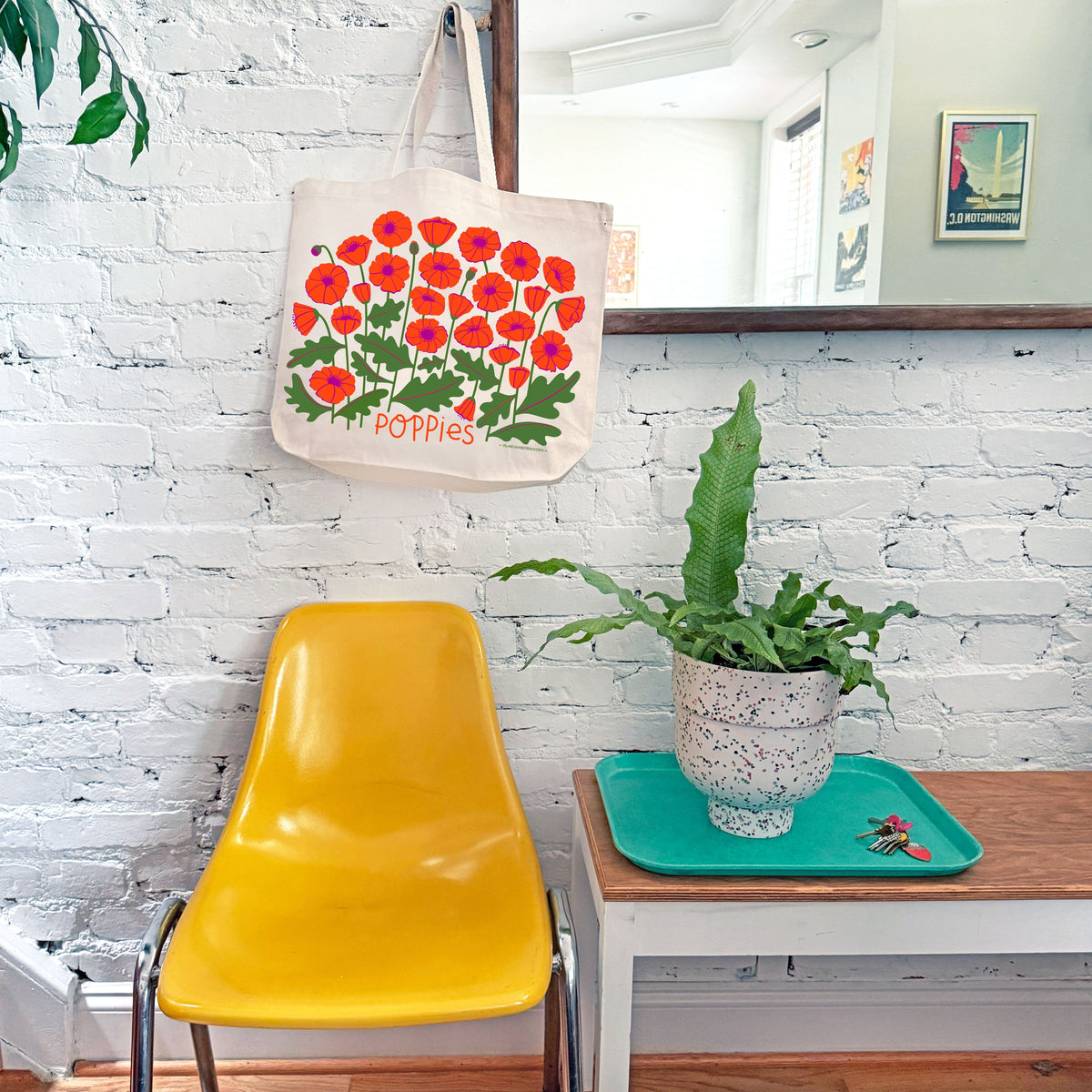 White canvas tote bag hanging with red-orange poppy floral design and “Poppies” text.