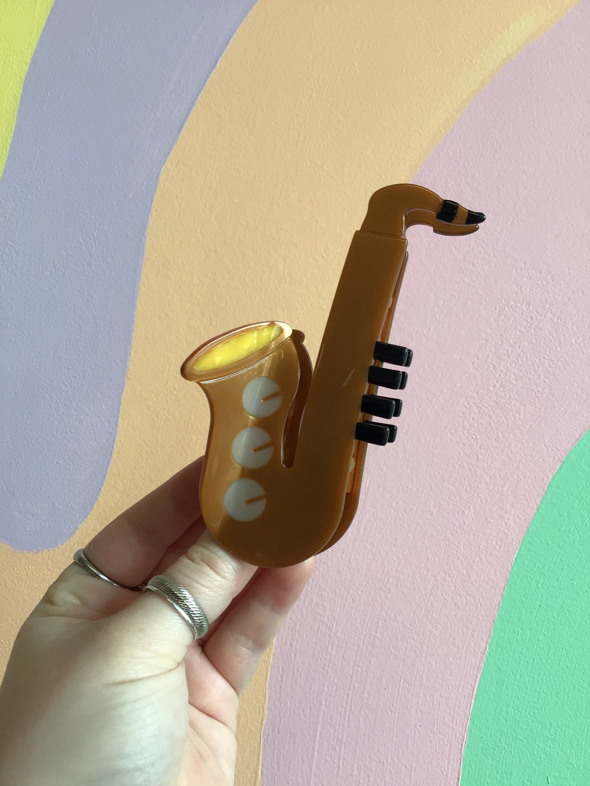 Gold saxophone-shaped hair claw with black stripe and glossy finish