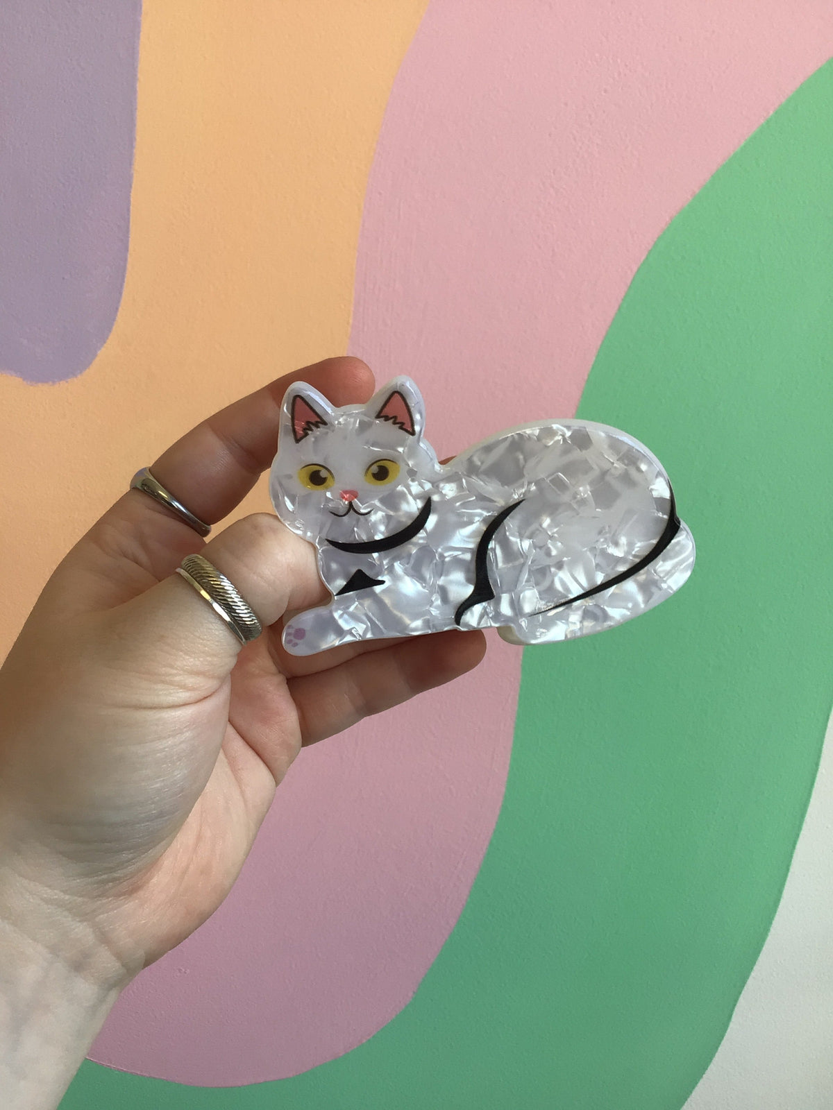 Clear white cat hair claw with black tail tip, yellow eyes, and pink nose