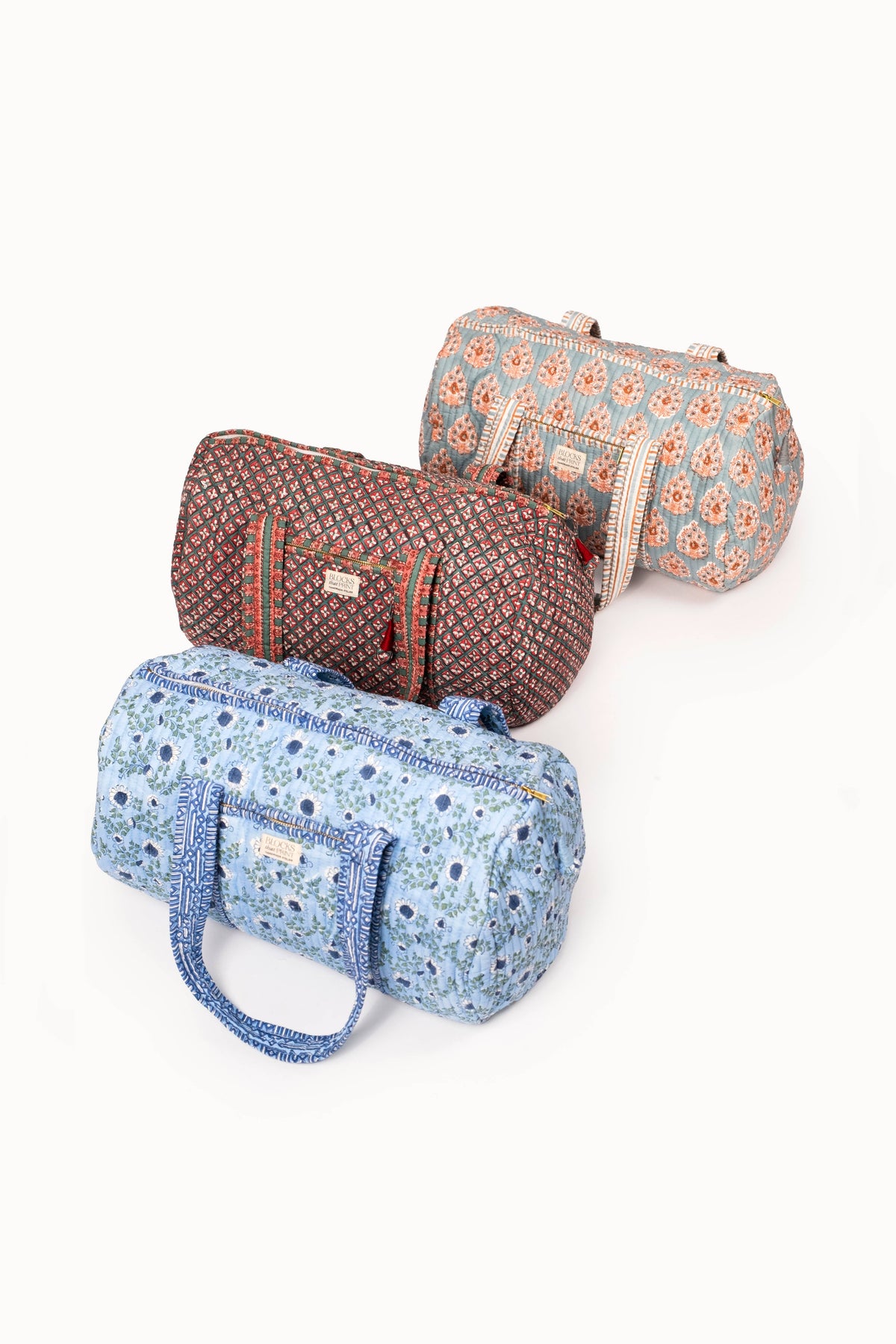 Assorted quilted block print duffle bags with zipper closures, blue and rust fabrics