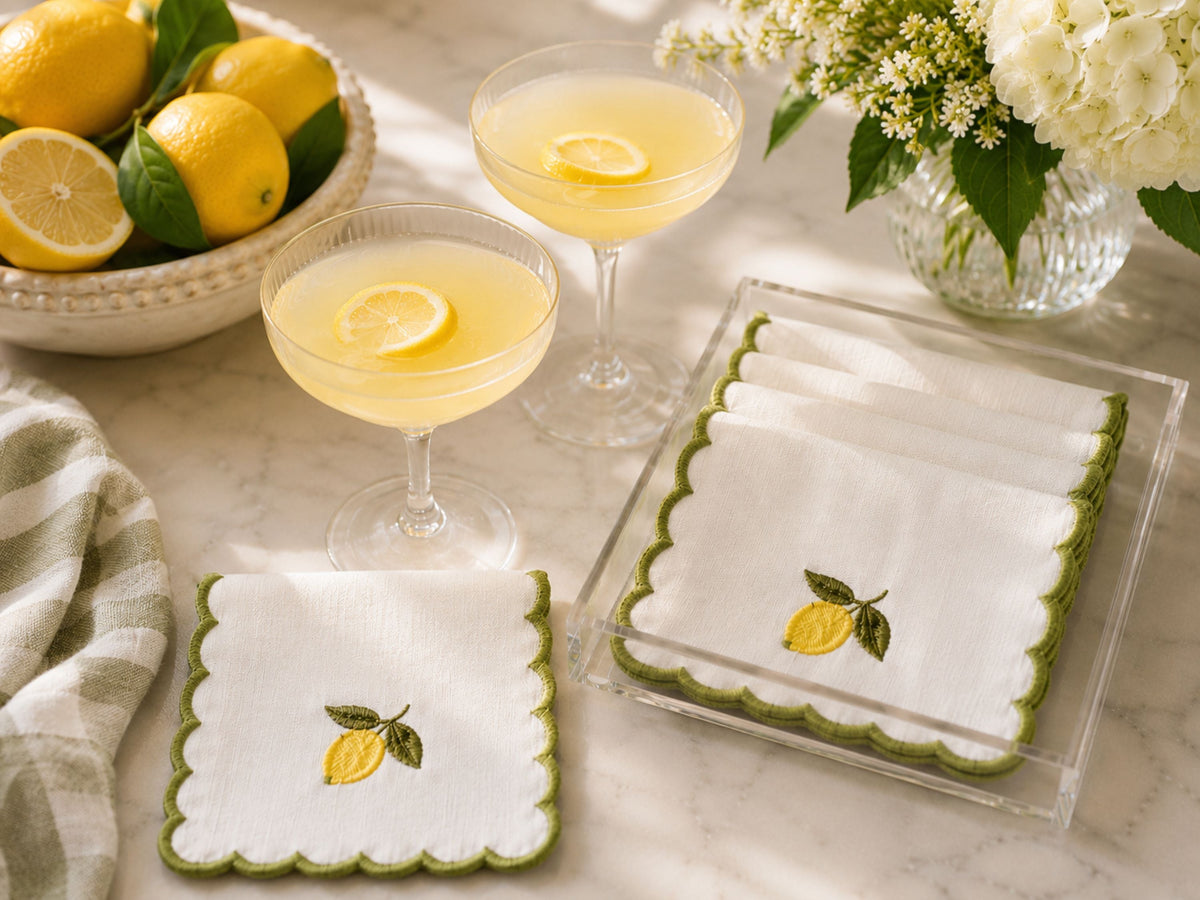 Embroidered cocktail napkins with lemon-and-leaf embroidery, white fabric and scalloped green edge