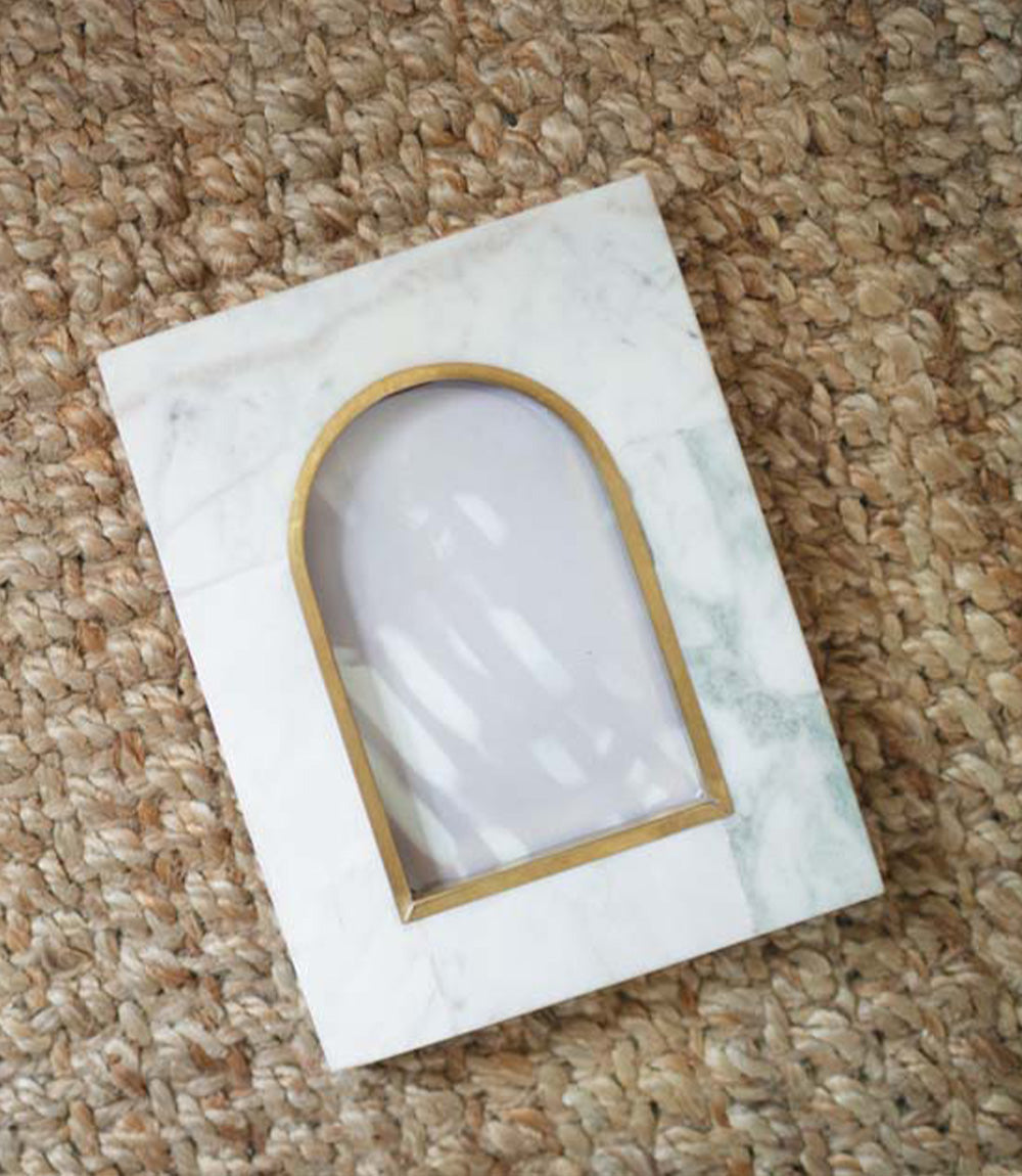 Arched white marble photo frame with brass gold trim, angled view