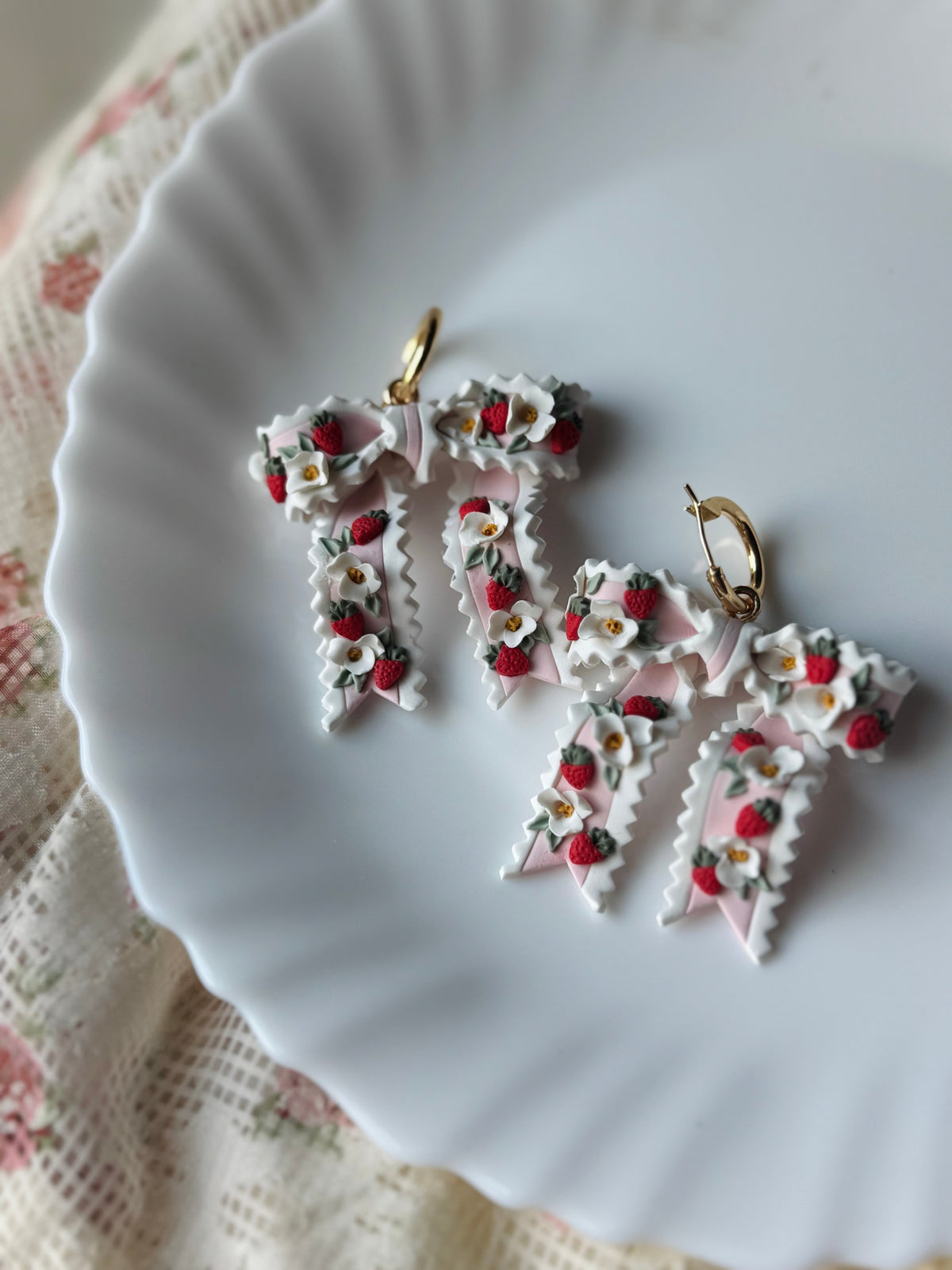 Strawberry ribbon charm earrings with strawberry and leaf details on gold hoop hooks