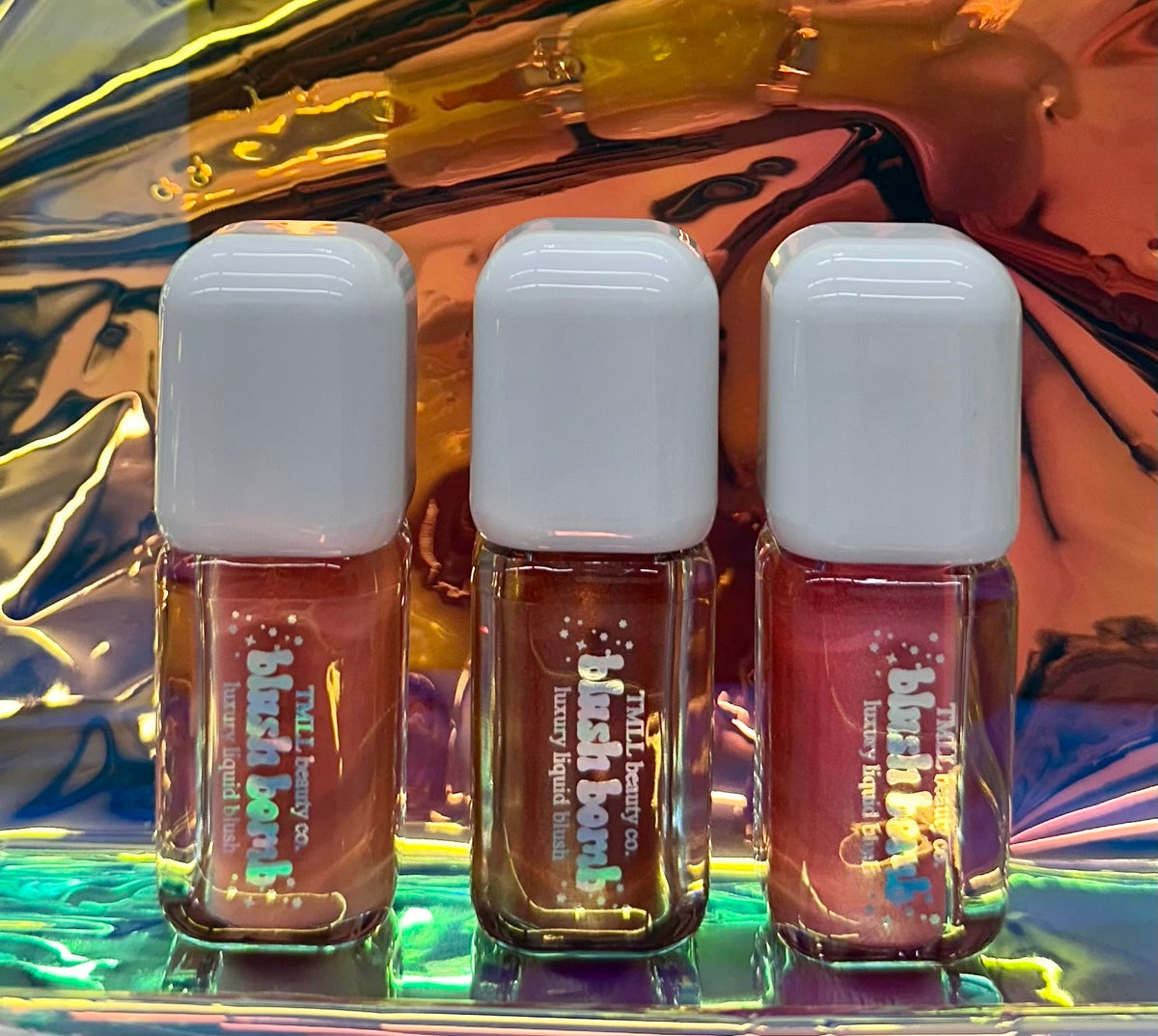 Three liquid blush mini bottles with white caps in pink, berry, and mauve tones.