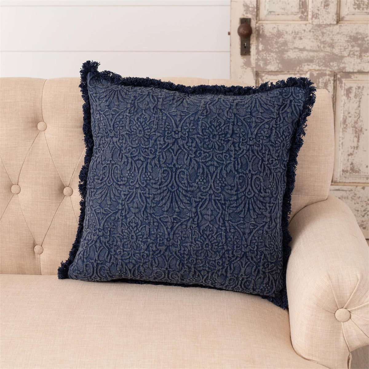 Blue indigo medallion throw pillow with quilted texture and dark fringe trim.