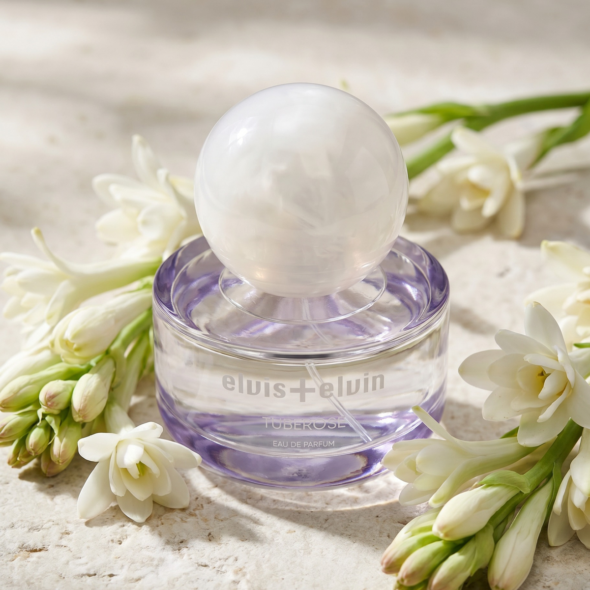 Tuberose eau de parfum bottle with white cap beside cream tuberose blooms