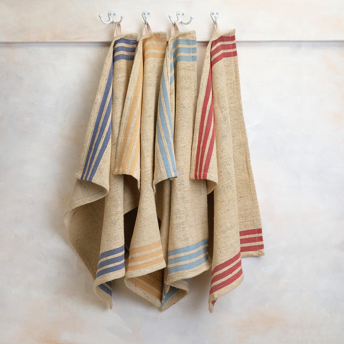Handwoven kitchen towels with blue and red striped ends hanging on hooks