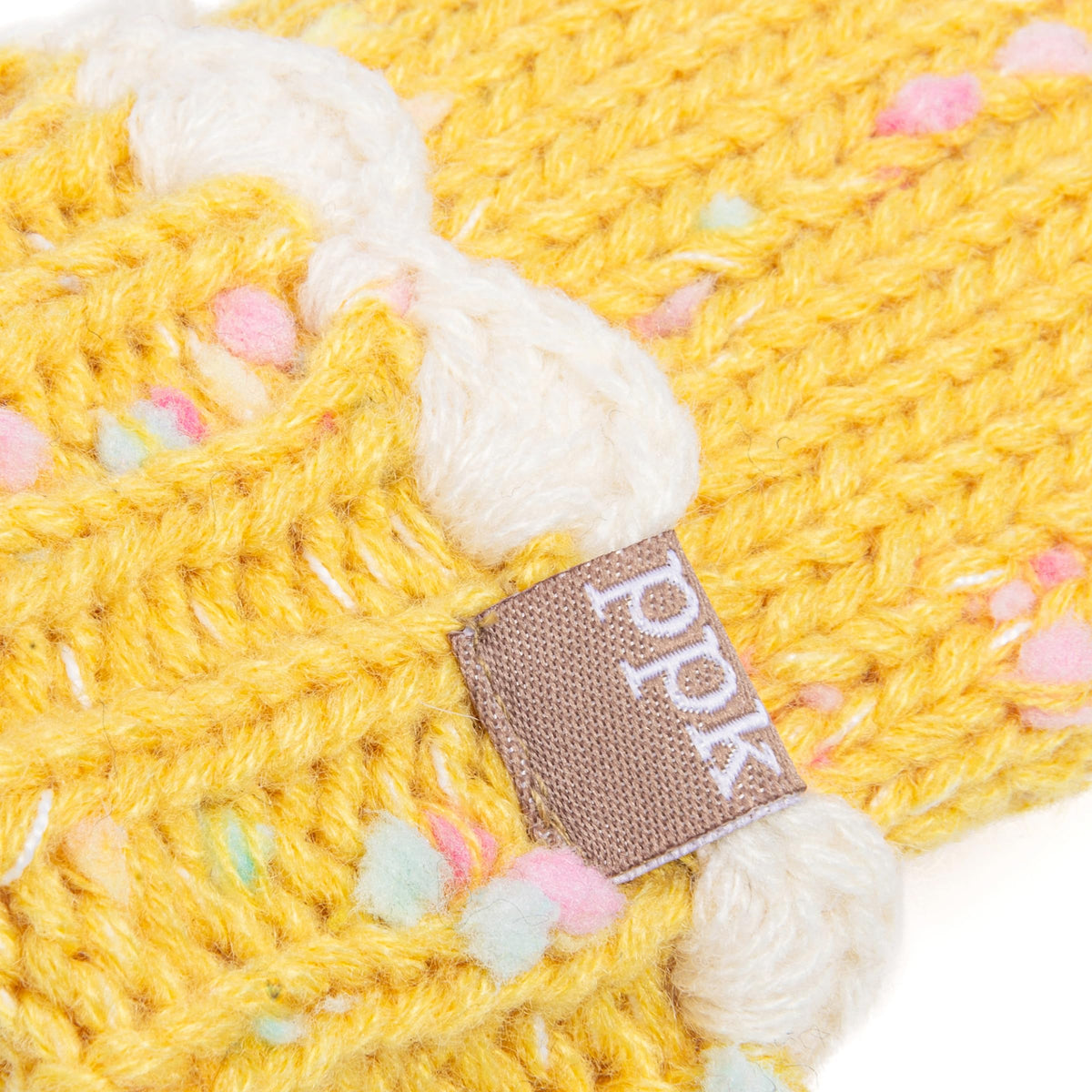 Yellow knit mitten cuff detail with cream scalloped trim, colorful flecks and logo tag.