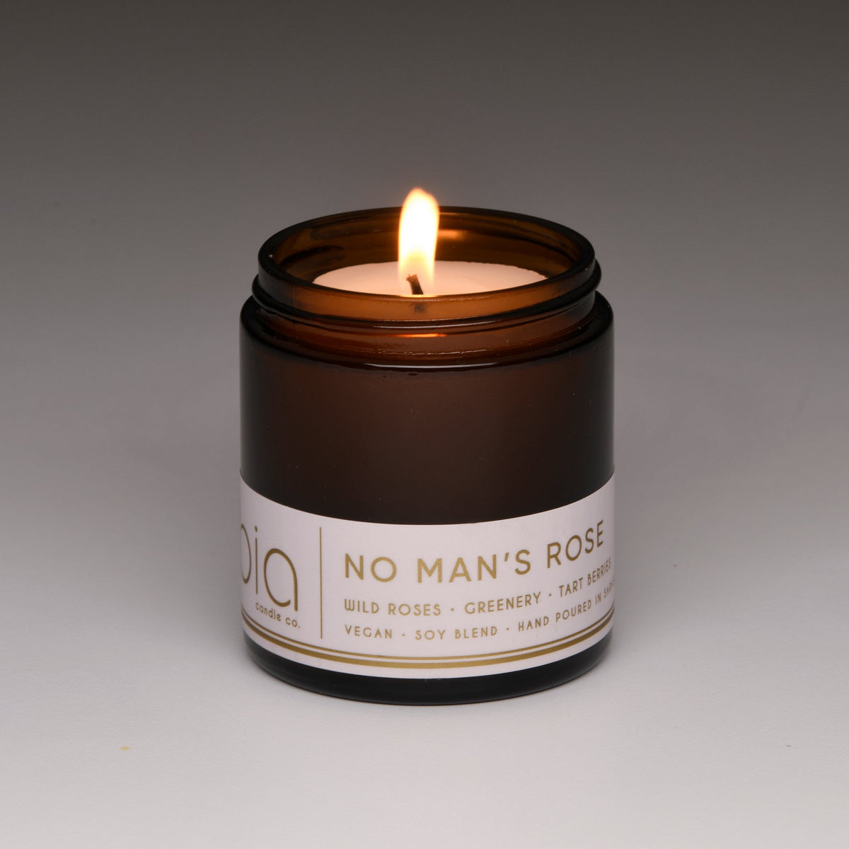 Amber soy blend candle in brown glass jar with label, lit flame