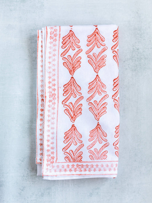 Orange-and-melon table throw with ornate leaf pattern, folded and shown flat