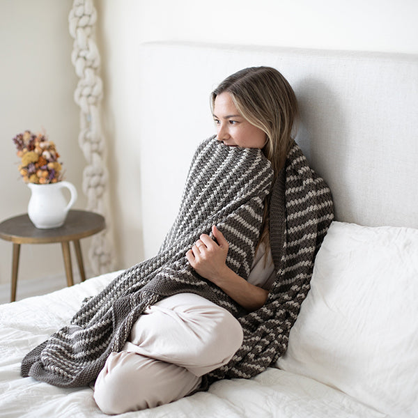 Dark gray and cream striped knit throw blanket with chunky texture