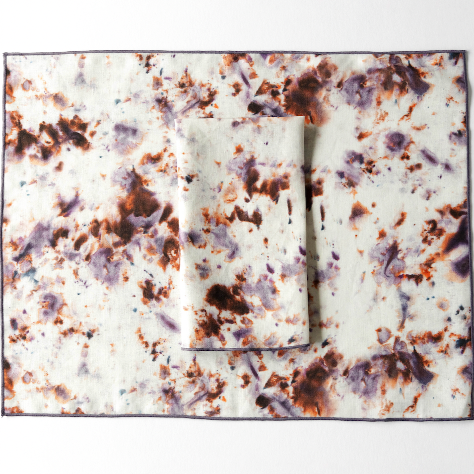 Marble rose placemat with plum trim; folded inner section on white mottled speckle fabric