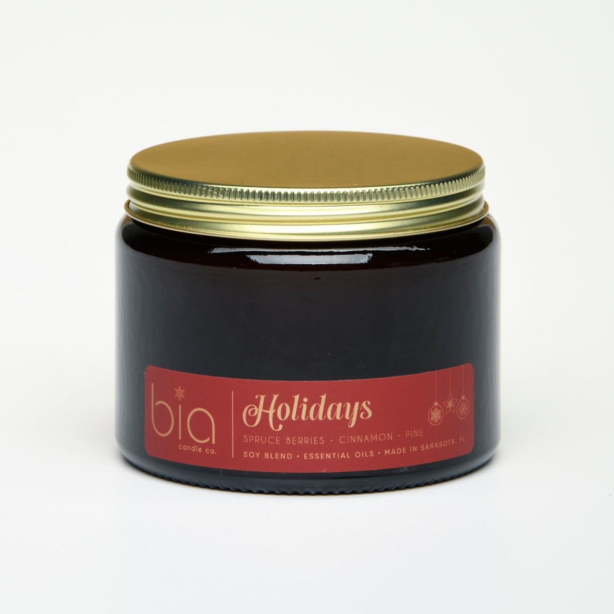 Amber candle jar with gold lid and Holidays label, dark glass container.