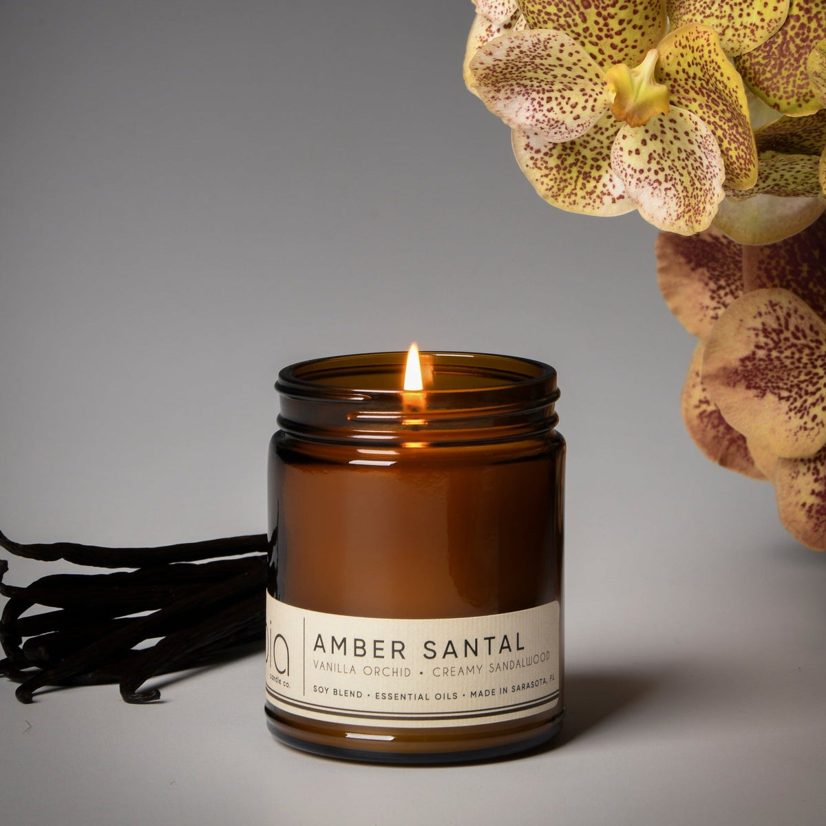 Amber soy blend candle in dark amber glass jar with lit wick and printed label