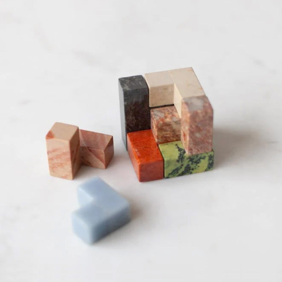 Gemstone cube puzzle with red and green marbled blocks, shown disassembled with pieces nearby.
