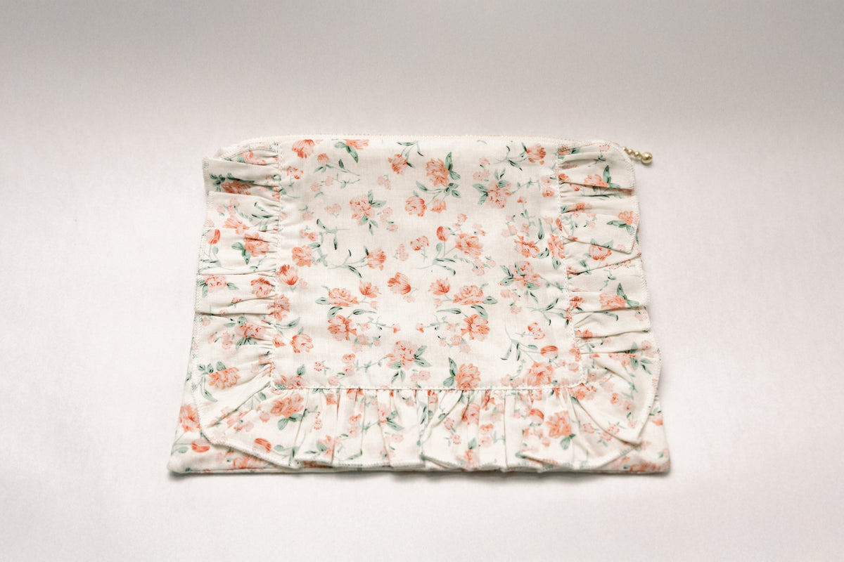 Floral ruffle zipper pouch showing top seam and gold zipper pull on light printed fabric