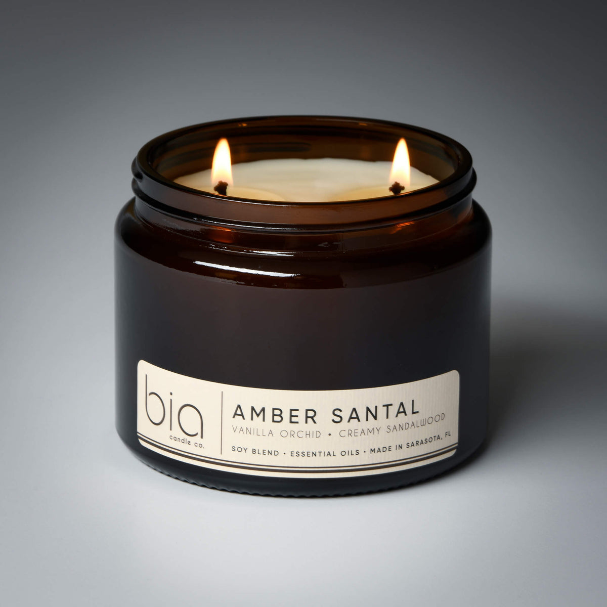 Amber glass soy candle jar with two flames and printed label, close up