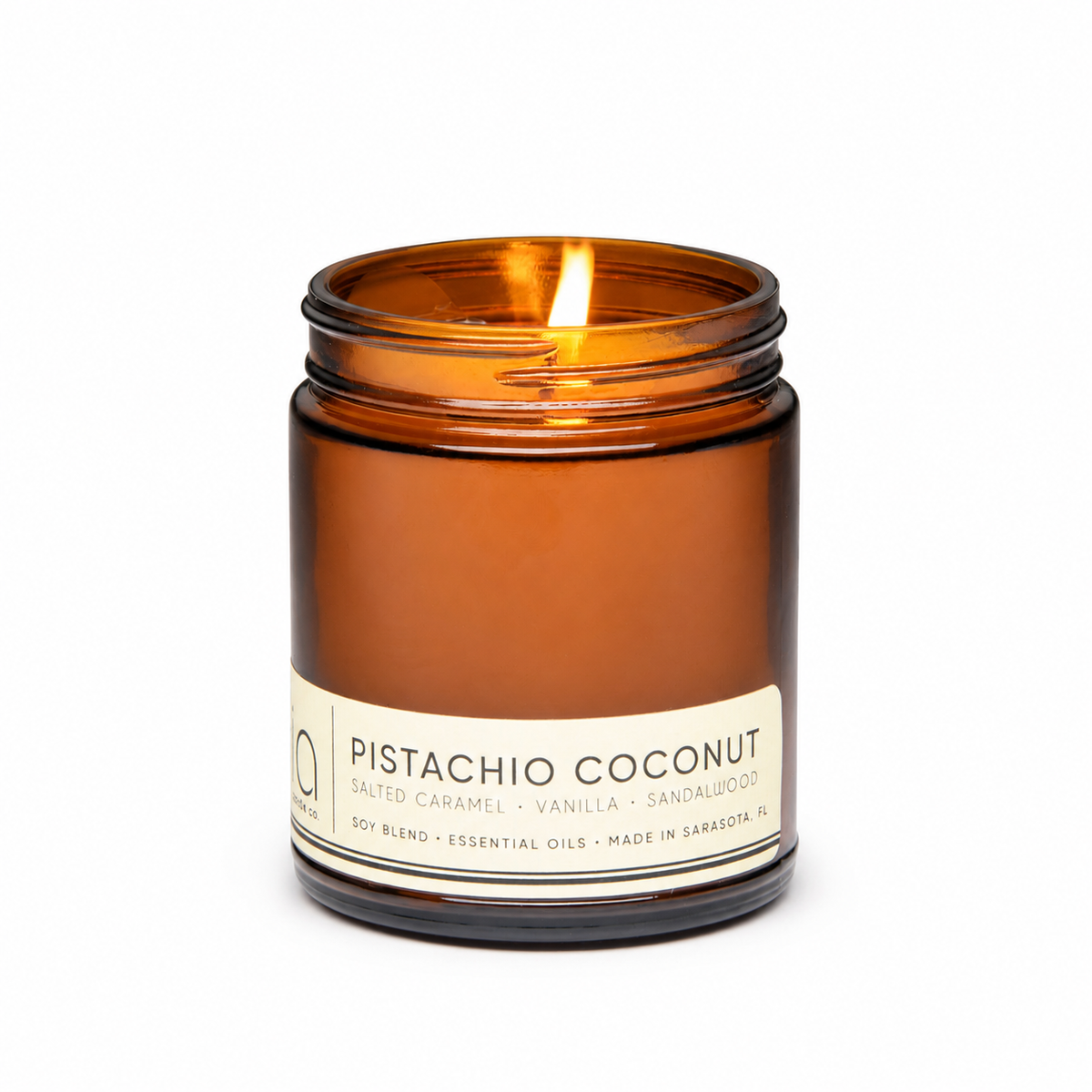 Lit amber glass jar candle with cream label and metal rim