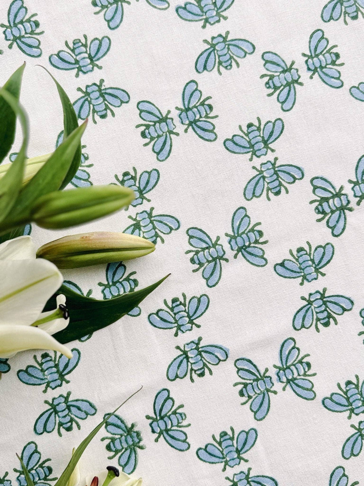Table throw close-up of blue and sage floral design on white fabric with corner fold.