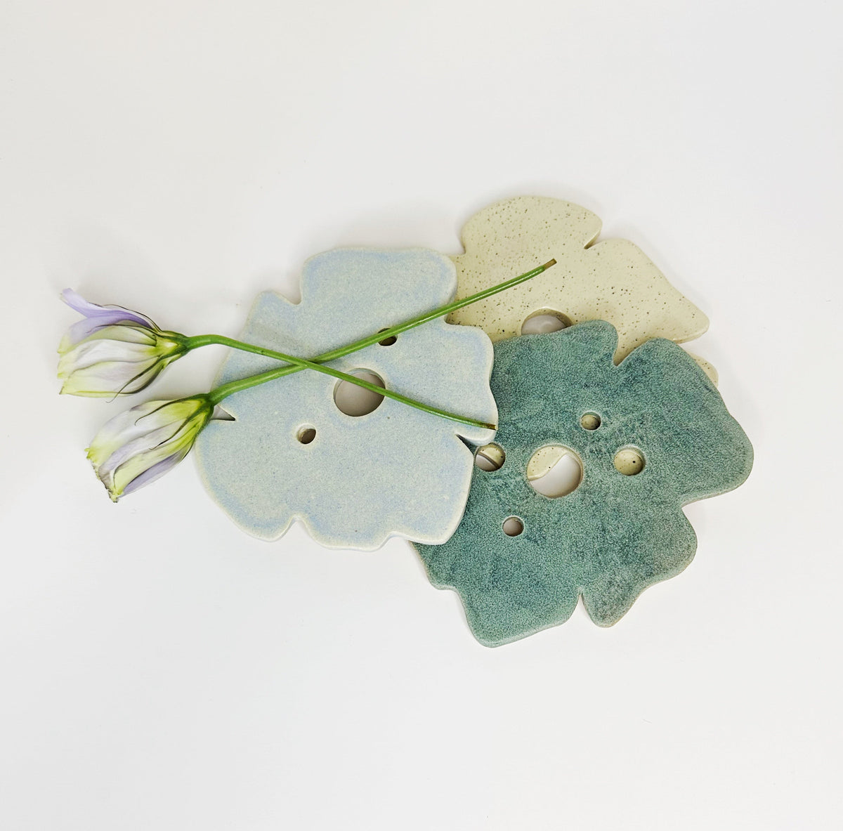 Pair of frog-shaped decor pieces in pastel blue and teal, with round holes