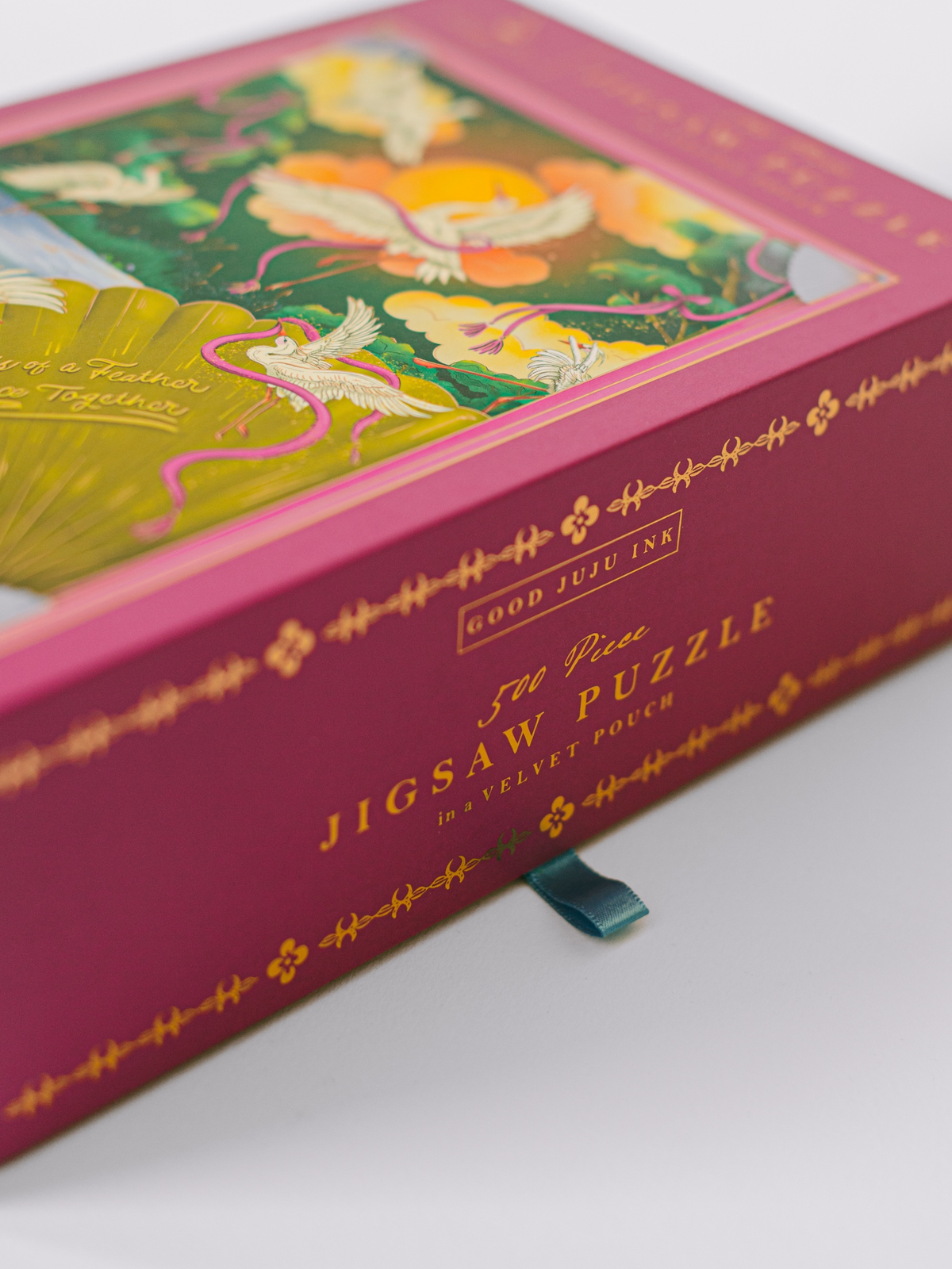 Jigsaw puzzle box side panel with gold script text and blue pull tab