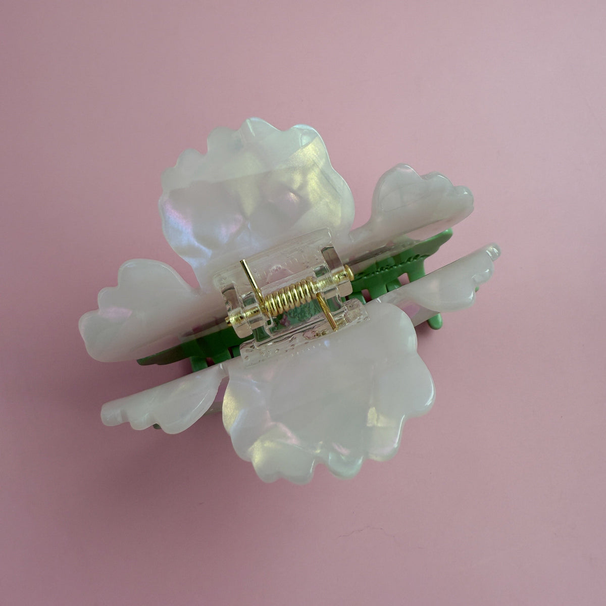 Opalescent floral hair claw with green base, visible hinge hardware and rhinestone studs
