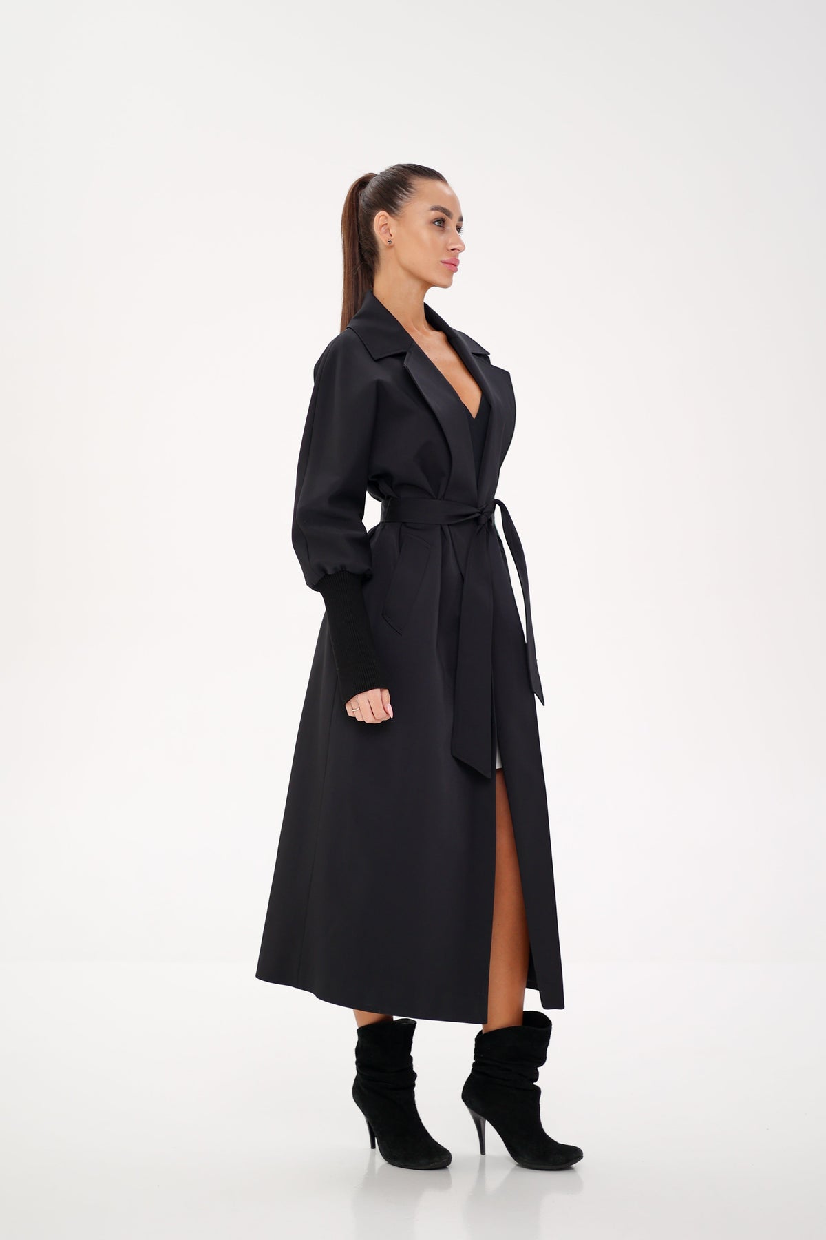 Side view of a black trench coat with a tie belt and long front opening