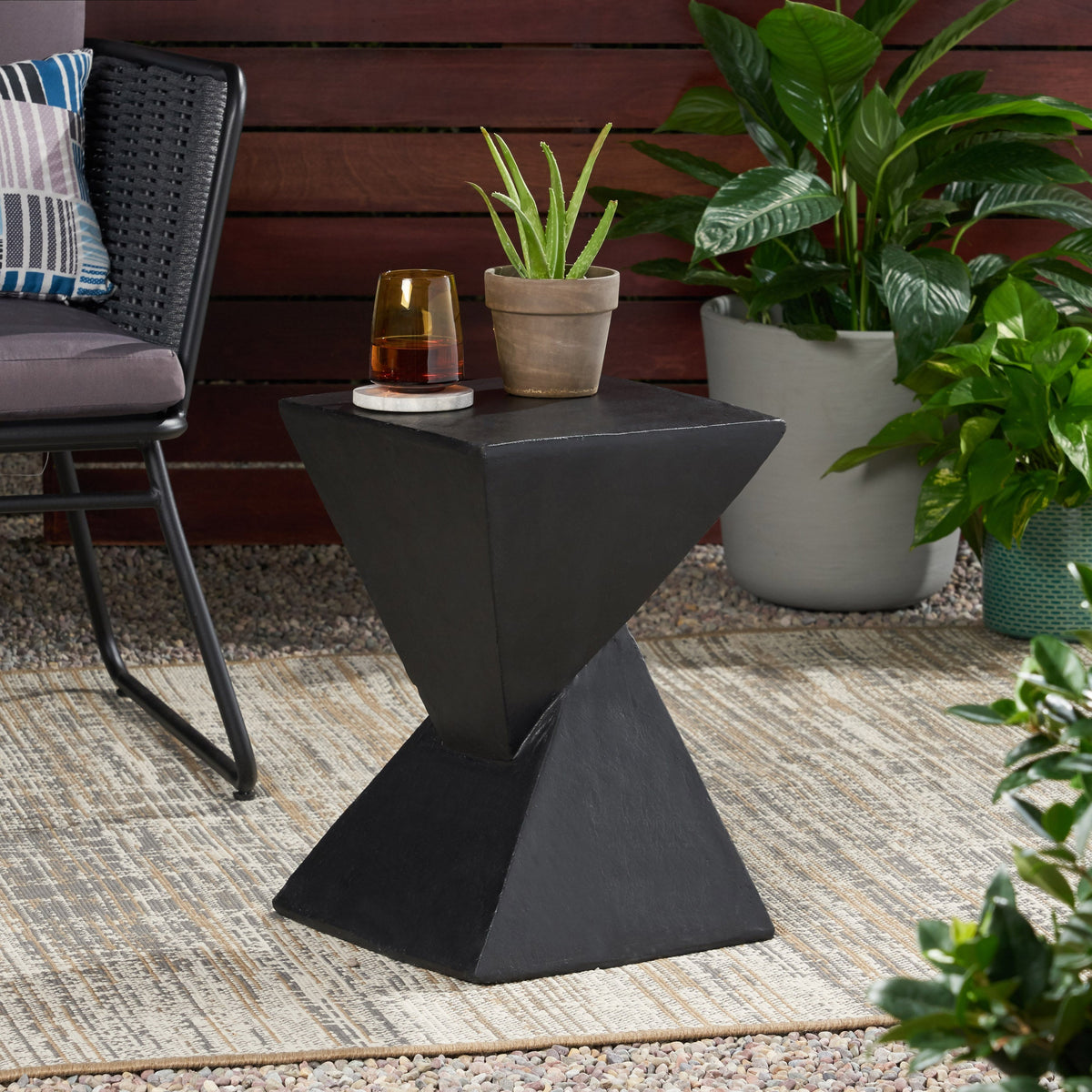 Black hourglass side table shown beside outdoor seating