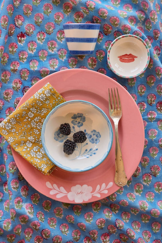 Small ceramic dipping bowl with painted red lips and blue dotted rim