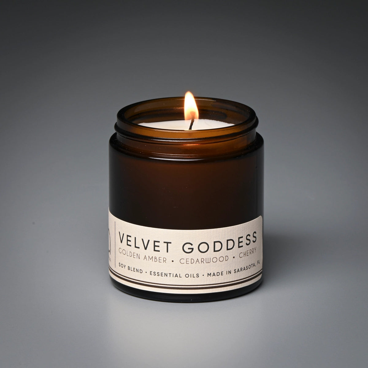 Amber glass candle jar with front label and single flame on top