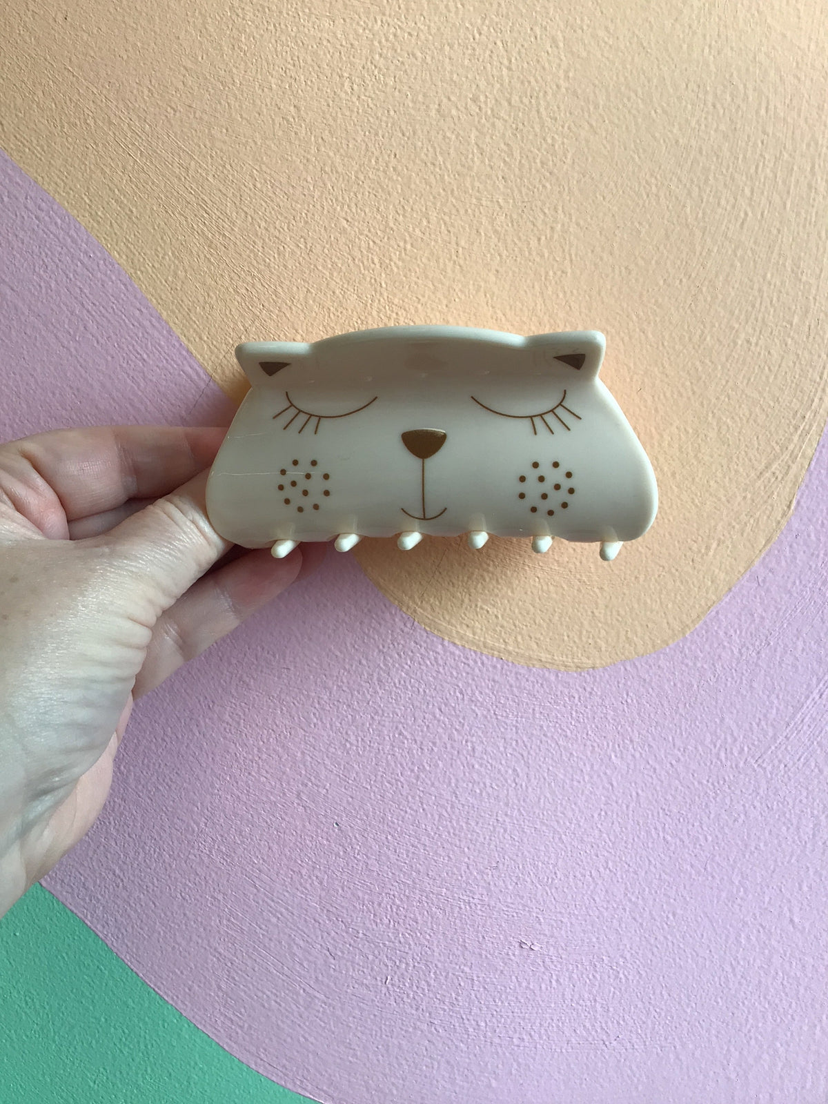 Cream kitty hair claw with closed-eye face and small dot details