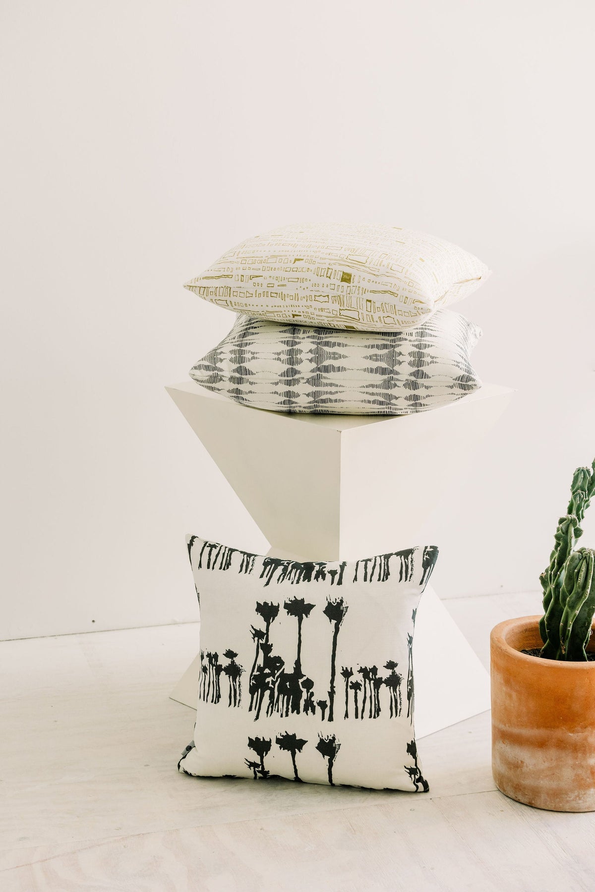 18x18 Bosque pillow with black animal silhouettes, shown stacked on a stand