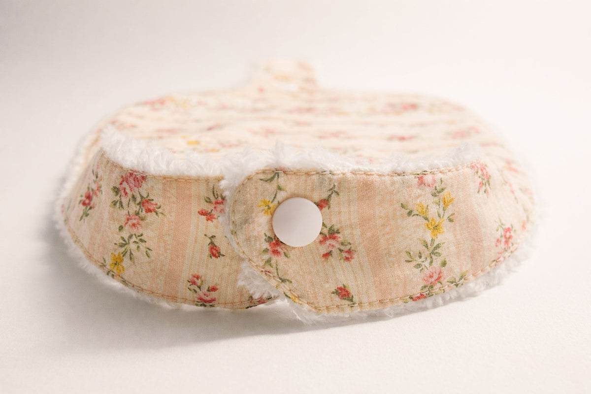 Pacifier bib snap close-up on Meadowlark Floral fabric, round grommet center