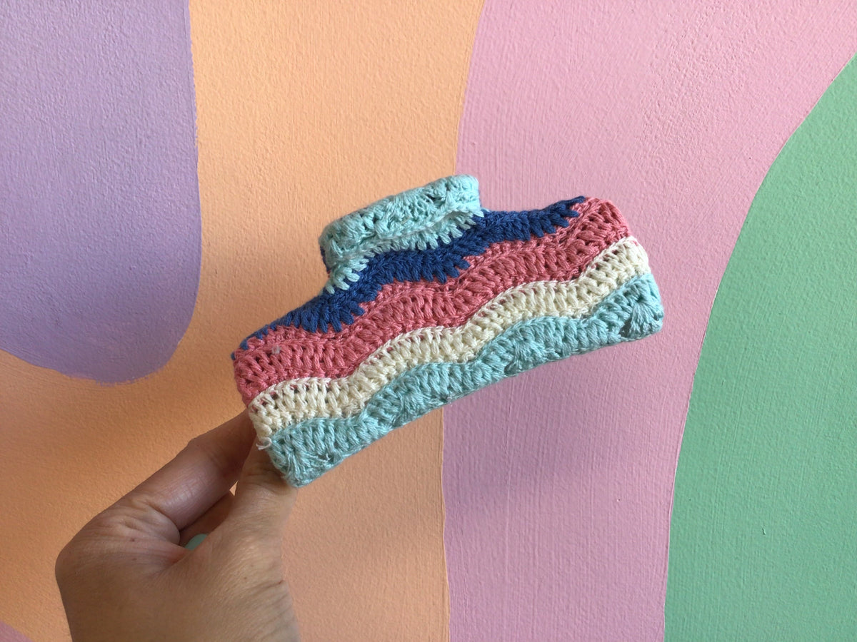 Crocheted hair claw with pastel stripes in pink, blue, teal, and cream