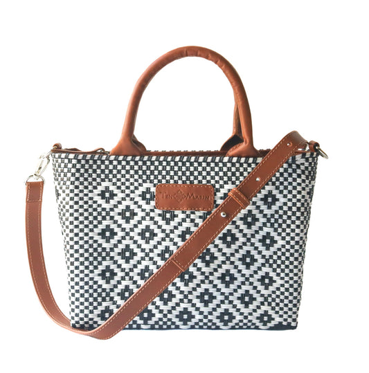 Small woven crossbody bag, black-and-white weave with tan leather handles and shoulder strap.
