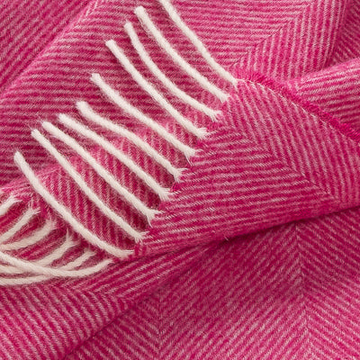 Pink herringbone throw corner with cream fringe and striped selvage detail