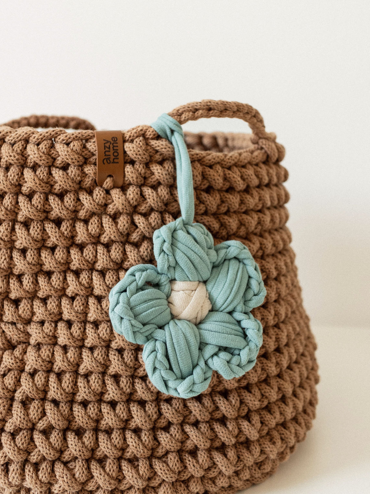 Close-up of brown crochet storage basket with teal braided flower detail